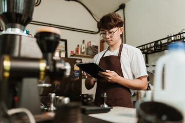 Asian man barista use digital tablet take orders service at coffee shop. SME business coffee shop concept.