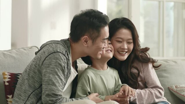 happy asian family sitting on couch enjoying time together at home