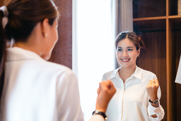 young adult asian self love cheer up pep talk standing looking in mirror before start working. girl...