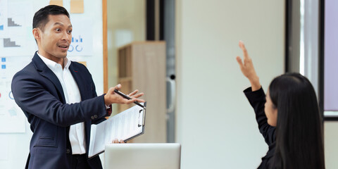 Fototapeta na wymiar Businessman in meeting or seminar pointing towards woman raising hand to say a question.