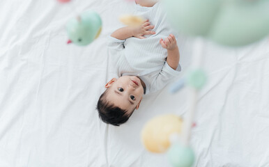 Top View, Adorable Asian Baby Boy, 5 Months Old, Smiling and Enjoy Playing with Crib Mobile in Home...