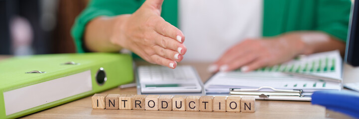 Letters introduction collected from wooden cubes and manager with hand ready for handshake.