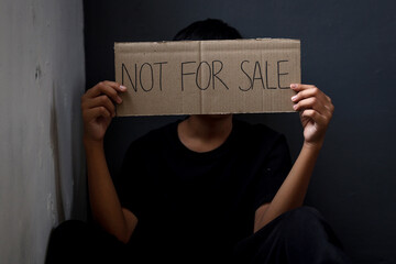 Kid showing cardboard with Not for sale text. Stop child abuse. Human trafficking concept