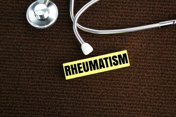 stethoscope and colored paper with the word rheumatism. joint pain concept. concept of medicine and...