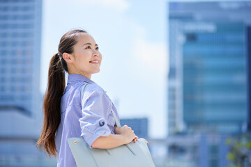 夏のビジネス街にて笑顔の日本人ビジネスウーマン