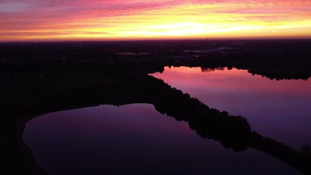 A drone is high above pink gold and purple reflecting waters at sunset in Mechels Broek near Antwerp, Belgium.