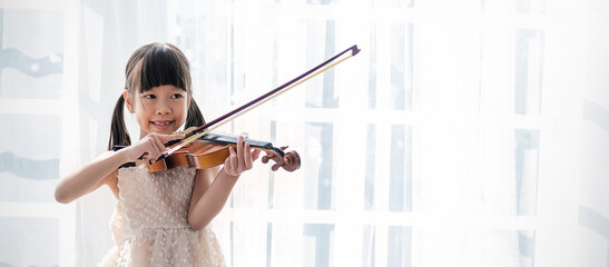 Portrait of young asian toddler little girl practice learning violin class room in white room at home or school isolated. Education, hobby leisure professional skill lifestyle concept © paulaphoto
