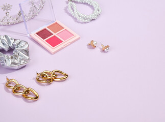 Various decorative women's jewelry, earrings for a fashionable look. Eyeshadow for luxury makeup. Copy space for text.