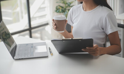 Asian Businesswoman Using laptop computer and working at office with calculator document on desk, doing planning analyzing the financial report, business plan investment, finance analysis concept.