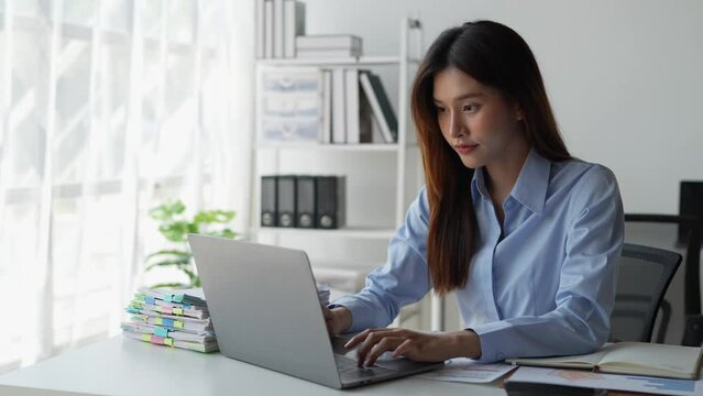 Happy young asian businesswoman using laptop computer to contact, chat, communicate, search, report, document business information to client, foreign investor. online business ideas.
