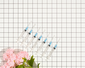 Top view of medical syringes for injections and beautiful pink flowers. Copy space for text.