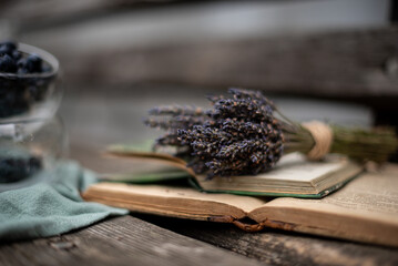 Autumn mood bunches of dried lavender on a wooden bench next to an open book and a green cloth napkin
