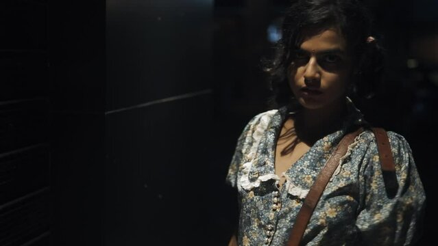 A beautiful woman wearing a bindi on her face in a nighttime environment with vehicles running in the background.