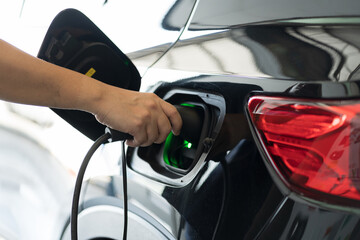 Hand of people holding DC - CCS EV charging connector to vehicle. Electric vehicle. Charging vehicle at charging station