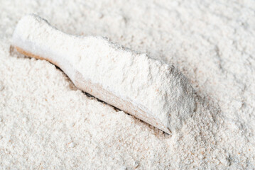 Baking background with flour in wooden scoop