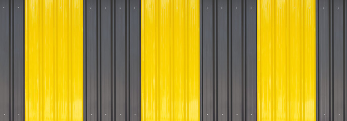 Panoramic view of yellow and black alternately colors pattern of corrugated metal wall background 