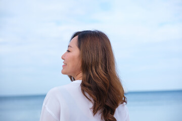 Portrait image of a beautiful young asian woman with the sea and blue sky background