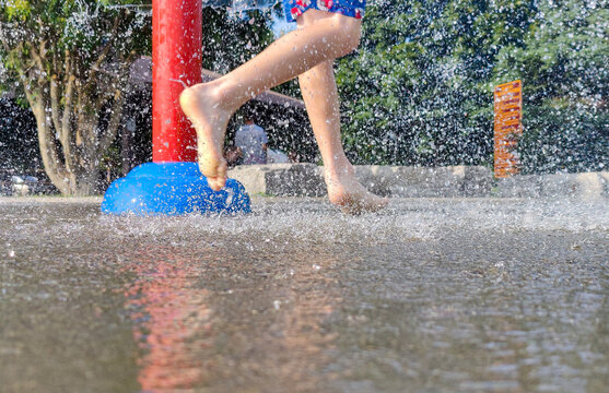 On a hot summer day, children are running around in the city's water splash pad playground.