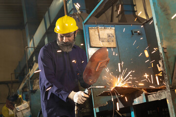 welder wearing protective hat, eyeglasses while working at factory