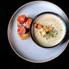 Creamy soup with bread, squid ink and tomato