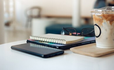 Coffee drink on table in cafe with mobile phone, eyeglasses and note books. people taking a break during a day with coffee drink in cafe