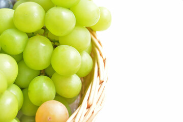 白背景とかごに盛られた色々な種類の大粒の葡萄