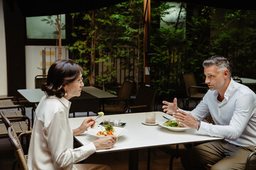 Business partners discussing project details during lunch in cafe