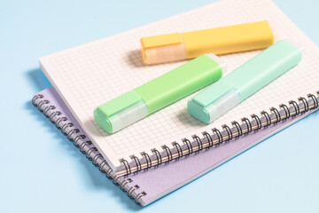 School supplies, back to school, multi-colored markers and notebooks on a blue background