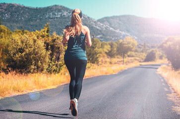 Woman running at sunrise on the road in country- sport, active woman concept