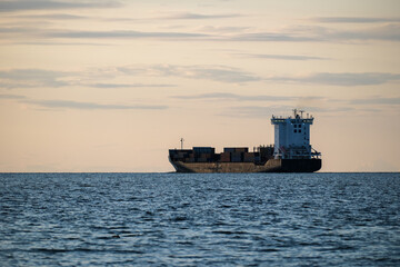 Container ship goes to sea against the background of the blue sky, Cargo transportation, Logistics import and export of goods.