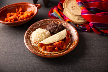 Chicharron en salsa roja. Pork rinds stewed in red sauce accompanied by rice and refried beans. Traditional homemade dish very popular in Mexico, this dish is part of the popular Tacos de Guisado.