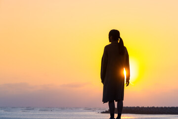 Silhouette of woman stand at sunset in the beach