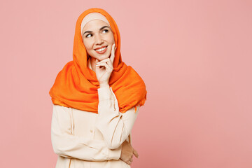 Young arabian asian muslim woman wear orange abaya hijab put hand prop up on chin, lost in thought...