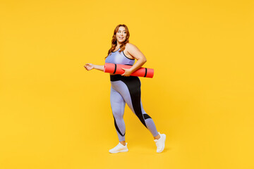 Fototapeta na wymiar Full body side view young chubby plus size big fat fit woman wear blue top warm up training hold yoga mat look aside on area isolated on plain yellow background studio home gym. Workout sport concept.