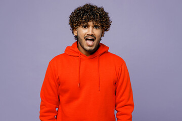 Young sad shocked displeased scared Indian man wear red orange hoody casual clothes look camera scream shout isolated on plain pastel light purple color background studio portrait. Lifestyle concept.