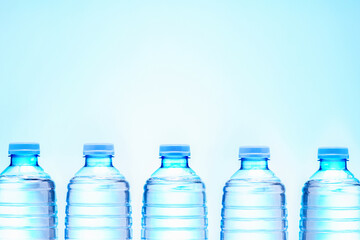 Row of drink water bottles on blue background with copy space.