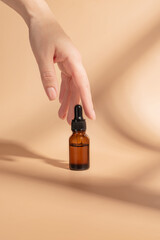 product package with serum and a woman hand in studio on a beige background to promote an antiaging treatment. Skincare, beauty and bottle with a female model. Mockup