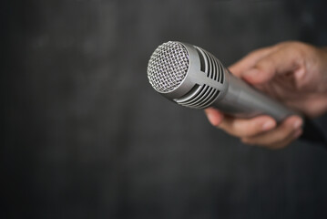 Silver microphone hold in hand. Microphone can amplify the sound lounder for the singer, orator,...