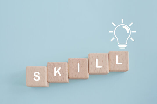 For up skilling and personal development concept. Skill training, education, learning, ability, knowledge, SKILL word   on wooden cube block with brighten lightbulb icon on grunge blue background