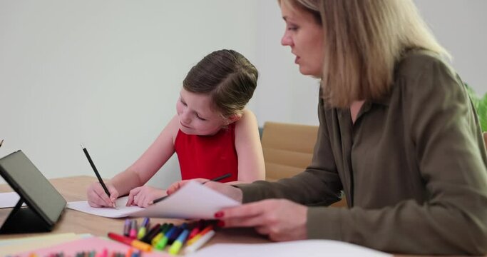 Mother and daughter paint picture together. Adult woman helping girl and learning to draw