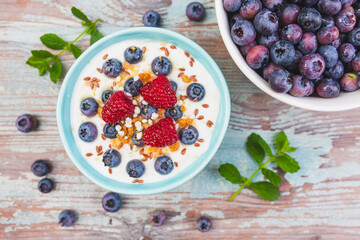 Yogurt with granola and fresh berries on the wooden table