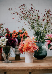 beautiful flowers in different vases placed on wooden table