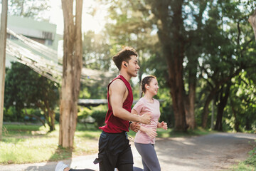 Two Asian young athlete man and woman in sportswear jogging exercise in park outdoor. Together...
