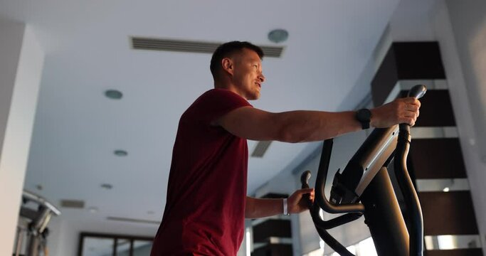 Man in cardio zone of gym is training on elliptical trainer. Sports fitness and health