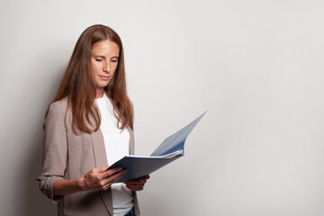 Confident business woman holding blue folder against white studio wall banner background