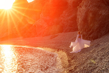 Mysterious woman silhouette long hair walks on the beach ocean water, sea nymph wind listens to the...