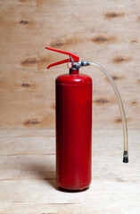 Obraz premium Red fire extinguisher on wooden background..