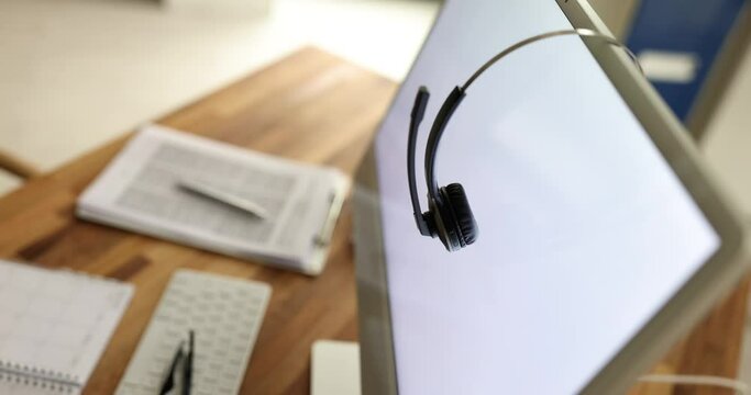 Black headset on computer monitor closeup. Call center concept