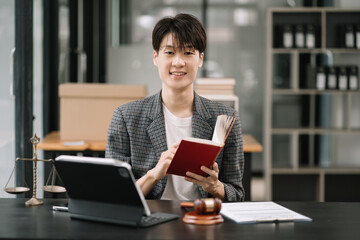 Male Legal counsel serious pensive reading a book law at desk in office.