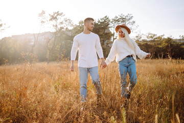 Happy couple in stylish clothes walk together, enjoy sunny autumn weather. Spend time together. Concept of rest, relaxation.